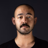 Portrait of a man with a mustache and short beard against a black background.